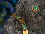 a statue of a buddha with a green bracelet on it