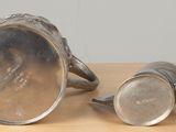 two silver cups sitting on a table next to each other