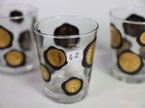 three glasses with gold coins in them on a table