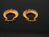 a pair of gold earrings on a black surface