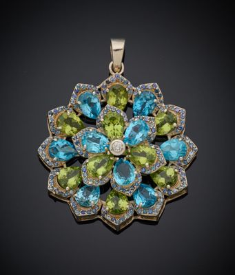 un gros plan d'un pendentif en forme de fleur verte et bleue sur fond noir