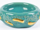 a green bowl with gold handles on a white surface