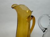 a yellow glass pitcher next to a clear glass pitcher