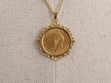 un collier en or orné d'une pièce de monnaie, porté par un mannequin