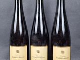 three bottles of wine are lined up on a table
