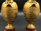 pair of antique brass vases on wooden bases on a black background