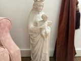 une statue représentant une femme tenant un enfant dans ses bras, à côté d'une chaise