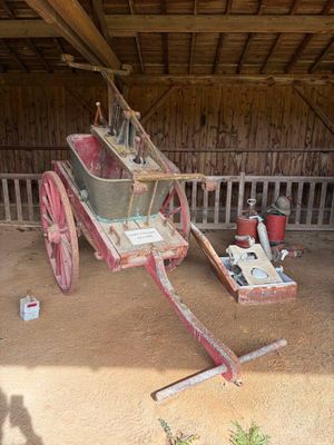 an old red wagon with a wooden seat in a barn