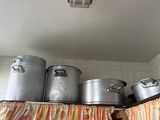 many pots and pans sitting on a shelf above a curtain