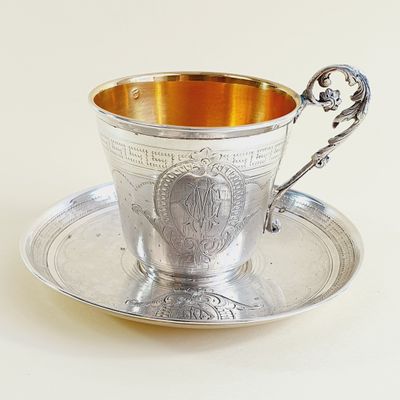 a silver cup and saucer sitting on a saucer