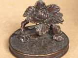 a close up of a bronze statue of a flower on a base