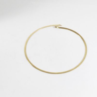 gros plan d'un bracelet en or sur une surface blanche
