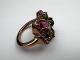 a close up of a gold ring with pink and green stones
