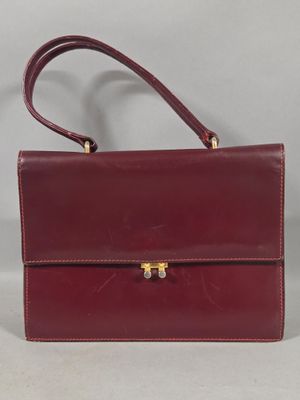 a red leather handbag with a gold clasp