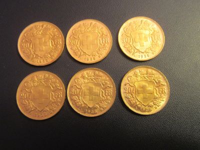 quatre pièces d'or ornées d'un blason, posées sur un fond noir
