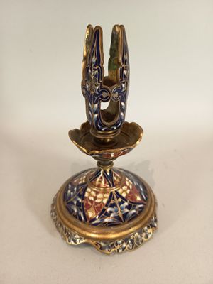 a gold and blue candle holder on a white table