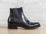 a close up of a pair of black leather boots on a wooden table