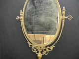 un miroir ancien en laiton posé sur un pied, avec un fond noir