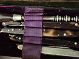 five knives in a purple case with a purple ribbon