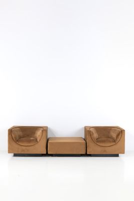 une photo d'un canapé et d'un pouf en cuir marron dans une pièce blanche