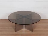 une photo d'une table en verre avec un piètement en métal posée sur un parquet