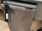 a small silver refrigerator in a kitchen with a black counter top