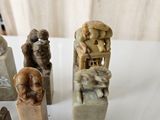 five sculptures of people sitting on top of a white table