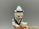 une figurine représentant un chat sur un bateau avec un poisson