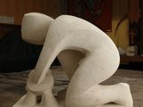 a sculpture of a man bending over on a wooden table
