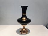 a black and gold vase sitting on a white table