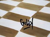 a painting of a brown and white checkered pattern with the word kluo written on it