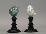 pair of glass seashells on black pedestals against a gray background