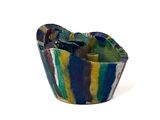 a colorful bowl with a spoon in it on a white surface