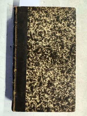 un vieux livre posé sur une table à côté d'une feuille de papier