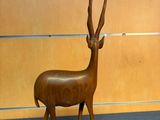a wooden sculpture of a antelope standing on a pedestal