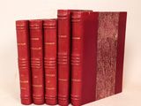 trois livres rouges sont empilés sur une surface blanche