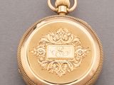 a close up of a gold pocket watch on a gray surface