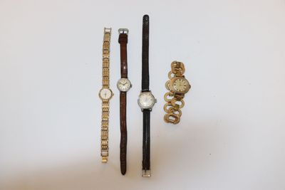 trois montres et un bracelet sont posés sur une surface blanche