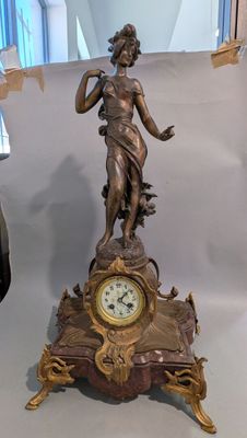 une statue de femme tenant une horloge sur une table