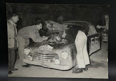 photographie en noir et blanc montrant des hommes travaillant sur une voiture dans un garage