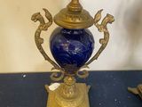 a blue and gold vase on a table with a clock