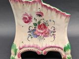 a small pink and green vase with flowers on it