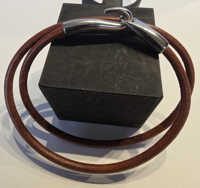 un bracelet en cuir marron muni d'un fermoir en argent, présenté dans un coffret noir