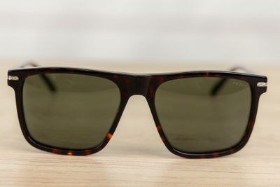 sunglasses on a wooden table with a white wall in the background
