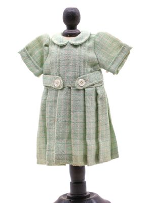 robe à carreaux verts posée sur un mannequin, sur fond blanc
