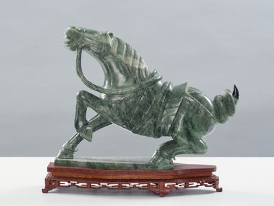 statue d'un cheval avec un cavalier sur le dos, posée sur un socle en bois