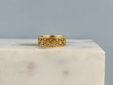 La bague en or repose sur un bloc de marbre blanc