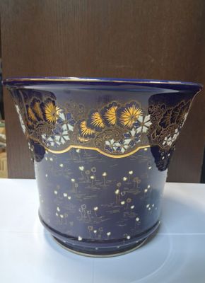 un vase bleu orné de motifs dorés, posé sur une table