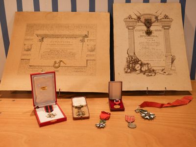 deux médailles et une médaille posée sur une table, à côté d'un livre ouvert