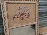a mirror with a picture of a bird on it next to a stool